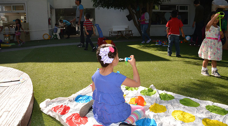 Niña sentada en el pasto, jugando con burbujas.