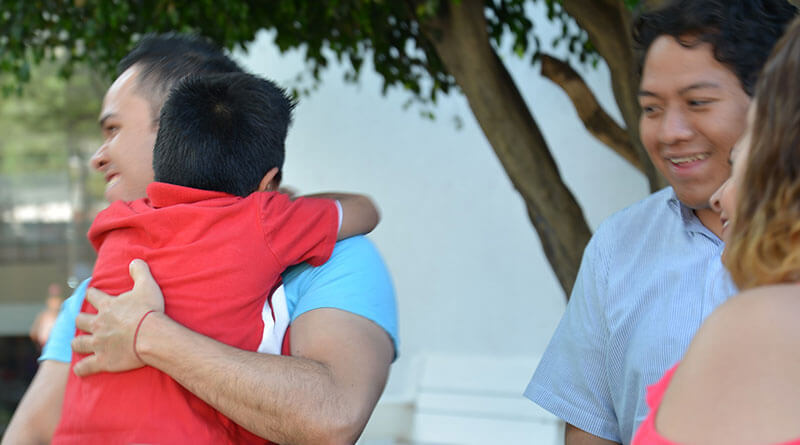 Hombre abrazando a niño pequeño.