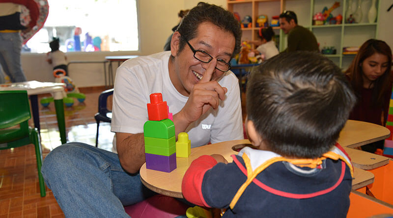 Señor jugando y divirtiéndose con niño pequeño.