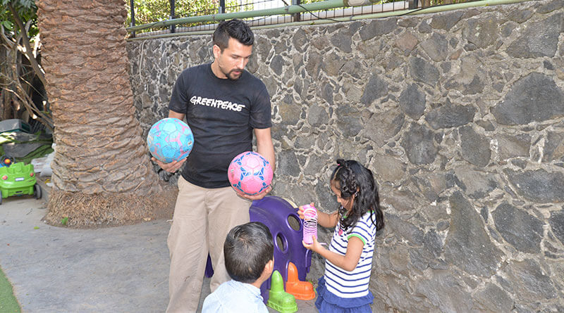 Hombre entregando juguetes a niños pequeños.