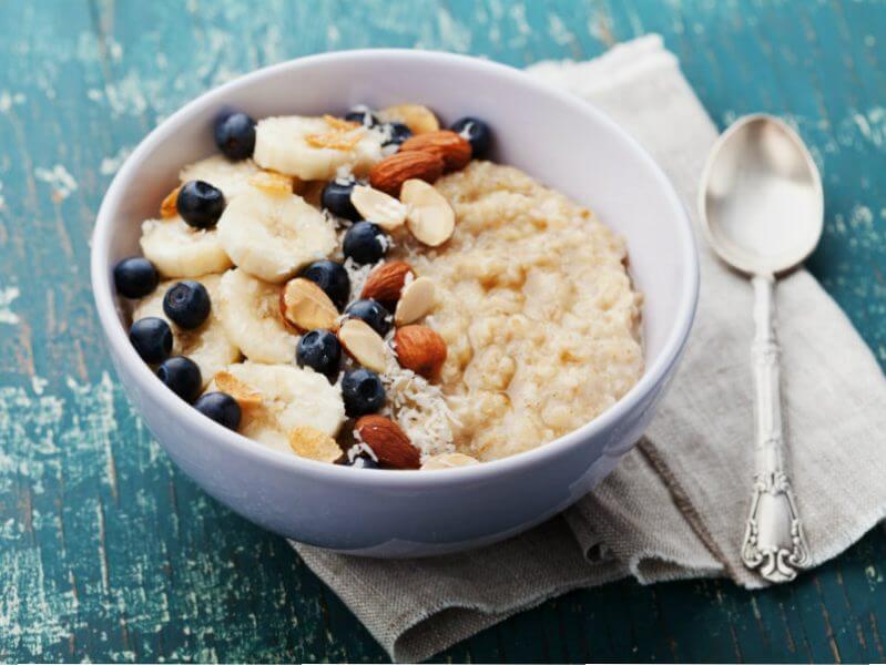 Bowl de avena con leche de coco, plátano, almendras y moras azules