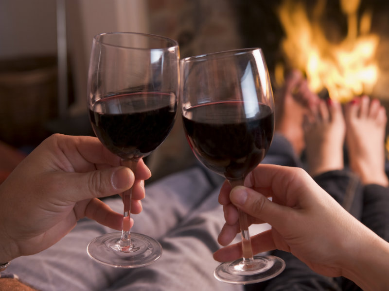 Una pareja juntos al fuego disfrutando una copa de vino